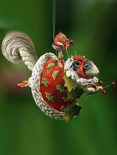 a squirrel ornament hanging from the side of a green leafy tree branch