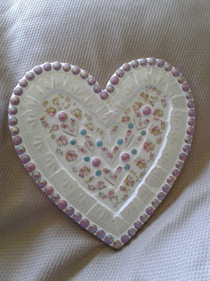 a decorative heart shaped dish sitting on top of a bed