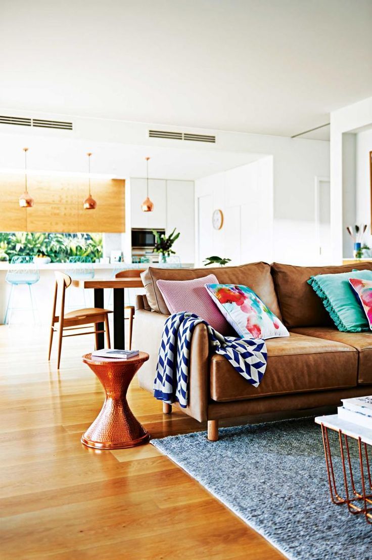 a living room filled with furniture next to a kitchen and dining room table on top of a hard wood floor