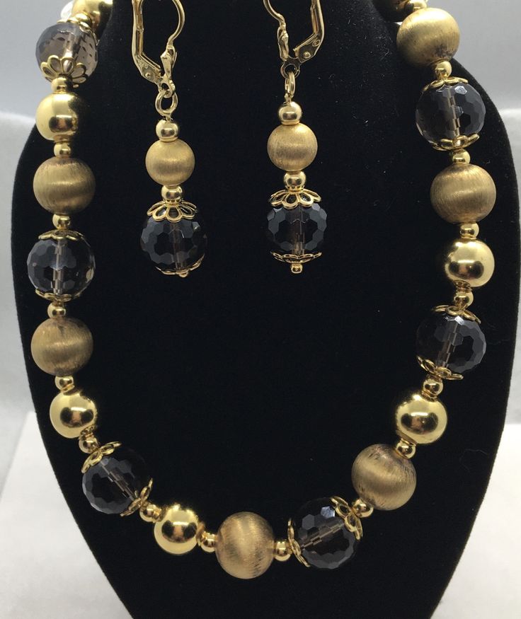 "Beautiful Gold over sterling smoky quartz & gold ball beads necklace & earring set Markings: Marked \"925 ITALY\" on clasp charm with an unidentified maker's mark, Marked \"925\" on clasp, Tested and Guaranteed Country of Origin: Italy Brand: Unknown Gram Weight: 61.9 Grams Metal Type: .925 Sterling Silver with Gold Wash Main Stone: Smoky Quartz Main Stone Measurements/Color: The smoky quartz beads on average measure 11.5 mm long from top to bottom and 12 mm wide. The stones have a semi Classic Gold Necklaces With Matching Earrings, Classic Gold Necklace With Matching Earrings, Bronze Jewelry With Polished Round Beads, Bronze Polished Round Bead Jewelry, Bronze Jewelry With Large Beads, Classic Gold Necklace With Faceted Beads, Gold Jewelry With Large Beads For Party, Gold Beaded Jewelry For Parties, Elegant Beaded Bronze Jewelry