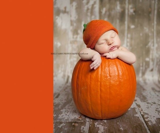 a baby sleeping on top of a pumpkin wearing a knitted orange hat with its eyes closed