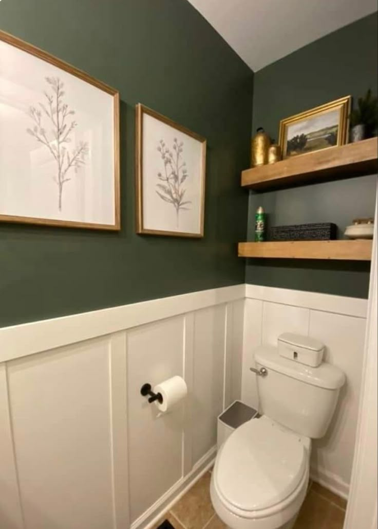 a white toilet sitting in a bathroom next to two framed pictures