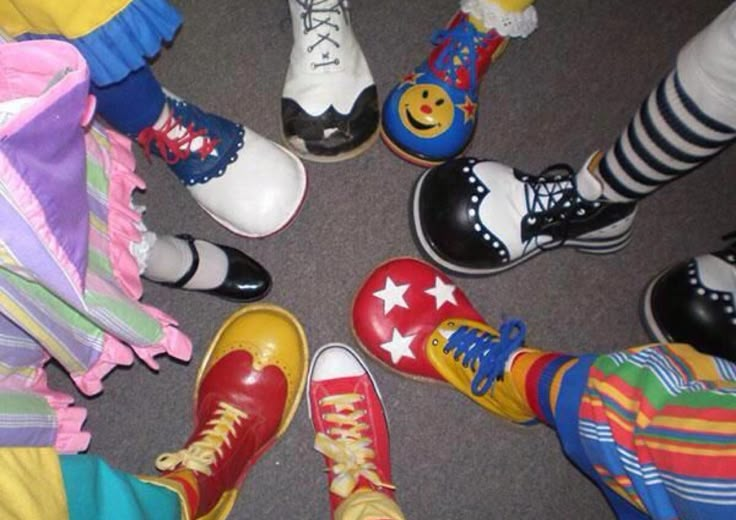 a group of people standing in a circle wearing brightly colored socks and colorful shoes with smiley faces on them