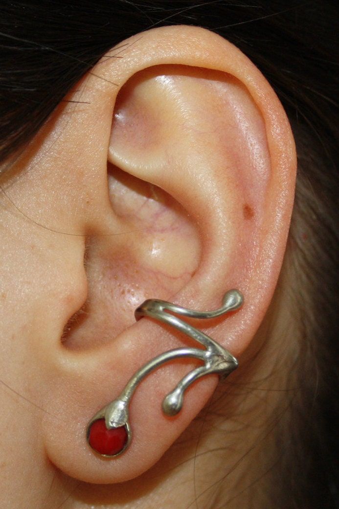 a woman's ear is adorned with silver and red stones