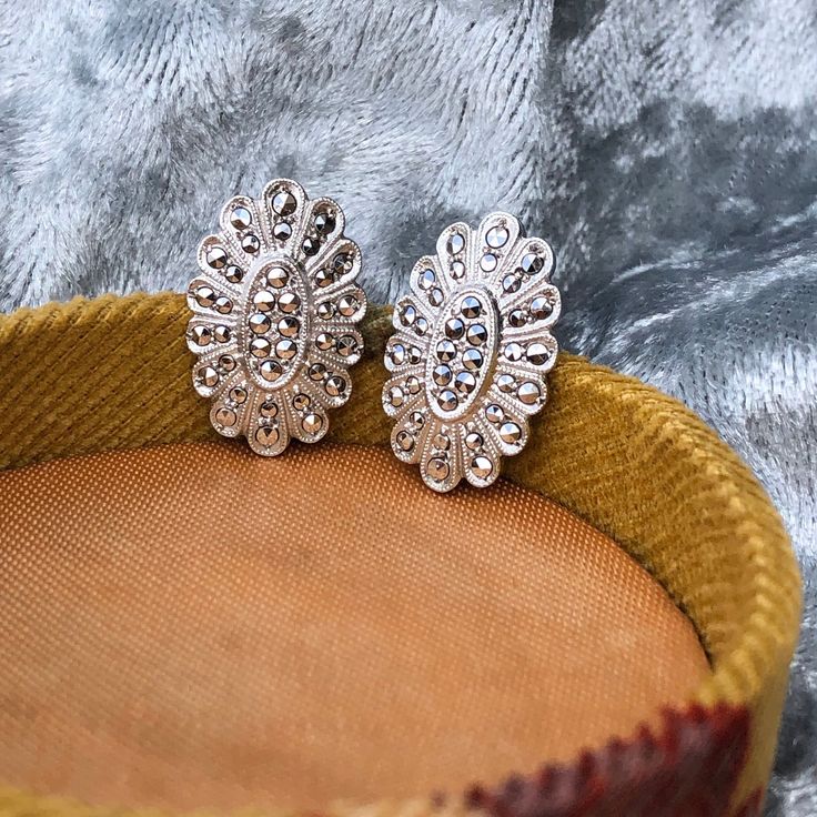 ༺♥༻✧OPEN FOR DESCRIPTION✧༺♥༻ Art Deco Style Sterling Silver (Rhodium Plated) Marcasite Screw Back Earrings with Oval Floral Form. Overall in excellent pre-loved condition, shows minimal surface wears and shiny rhodium coating appears to have no tarnishes. Rhodium plated sterling silver is considered more desirable since it is less likely to tarnish, and will appear shinier with a mirroring effect, which will also enhance the appearance of any gemstones or details on the jewelry. Screw backs are easy to adjust to your comfort, as they will not pinch or pull your earlobes while clip-ons and pierced backs may do so. Art Deco style screw back earrings made by 1990s jewelry designer Masha. Full set of marcasites, no missing stones. - Marked "Sterling" and "MASHA" - Full Length measures 6/8 inch Luxury Silver Marcasite Jewelry, Vintage Marcasite Jewelry, Marcasite Earrings Art Deco, 1990s Jewelry, Minimal Surface, Romantic Jewelry, Romantic Jewellery, Screw Back Earrings, Art Deco Style