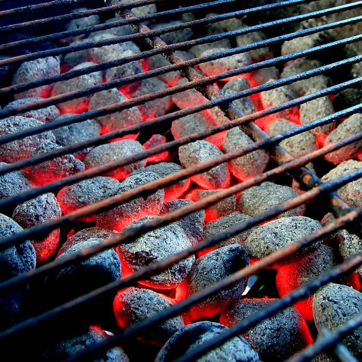 hot coals cooking on an outdoor grill with red light coming from the top and bottom