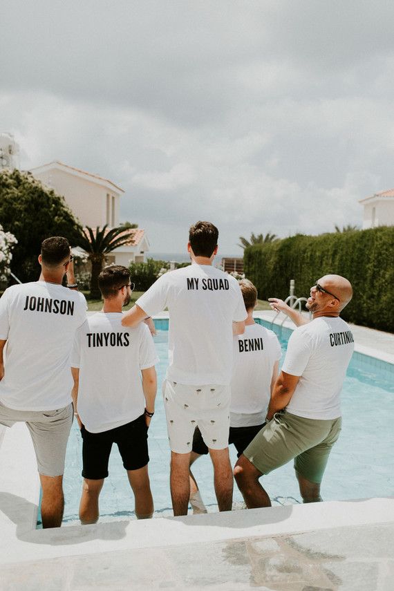 four men standing in front of a swimming pool wearing t - shirts that say my squad