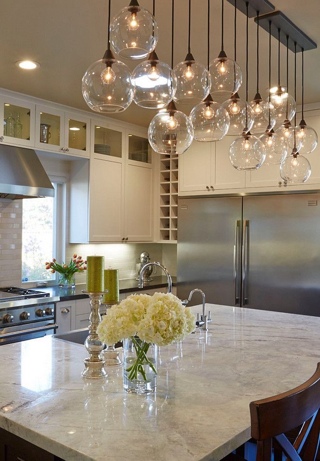 a kitchen with an island and lots of lights hanging from the ceiling