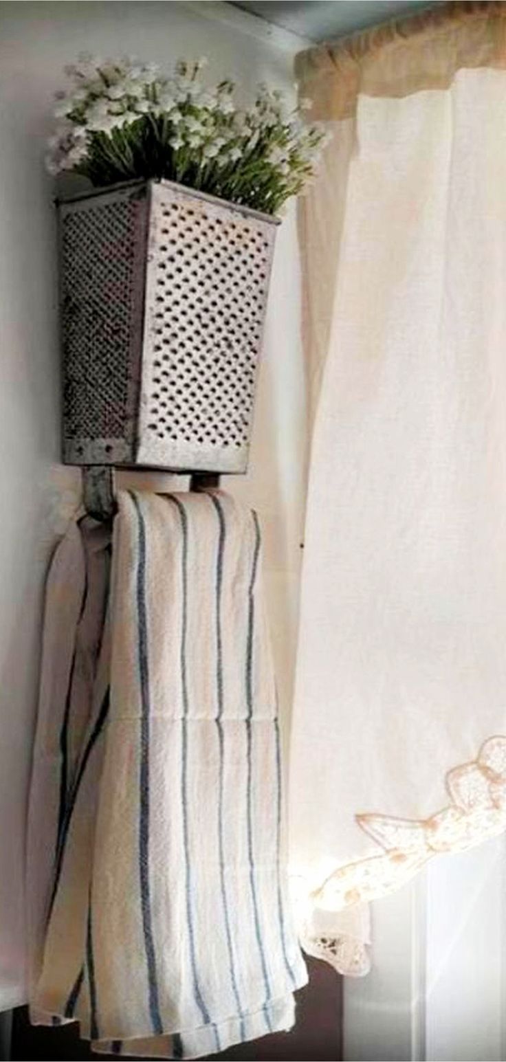 a basket with flowers sitting on top of a shelf next to a curtain and window