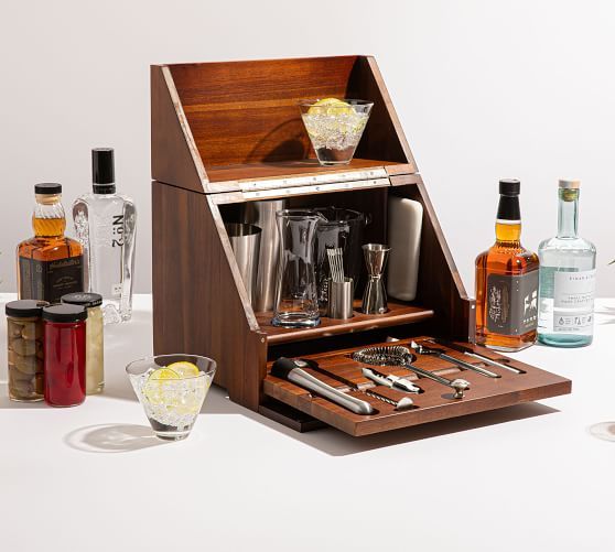 an open wooden box with liquor bottles and utensils in it on a table