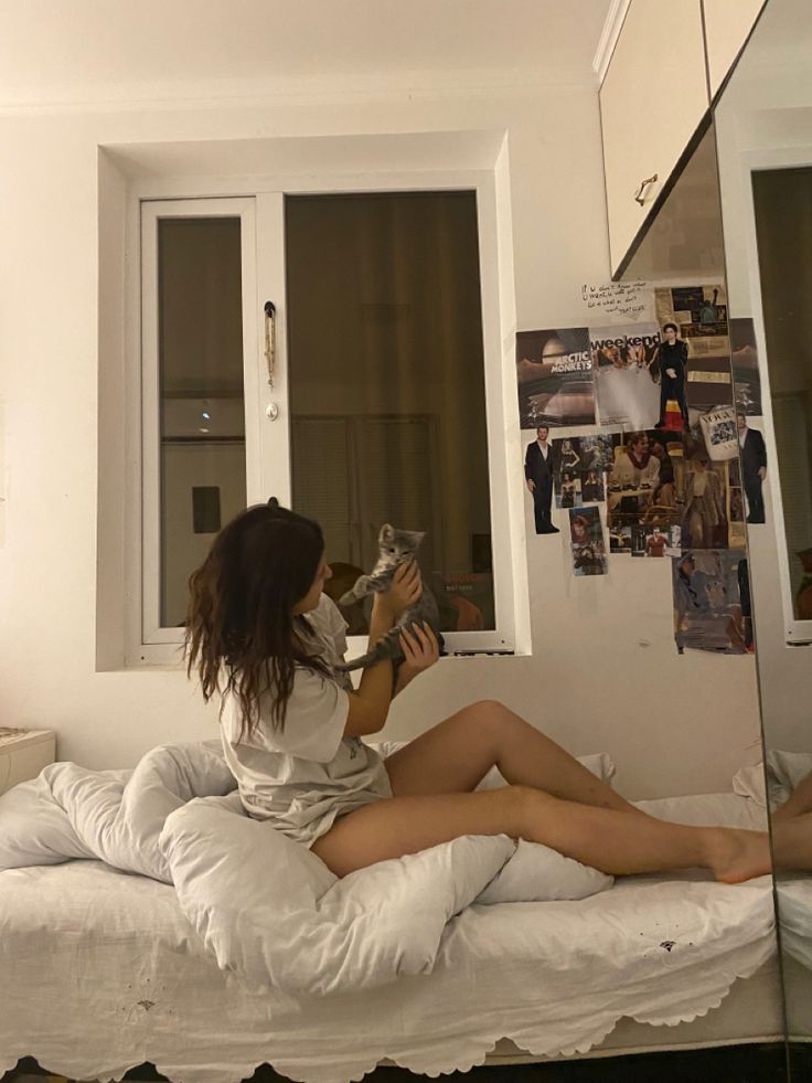 a woman sitting on top of a bed next to a window