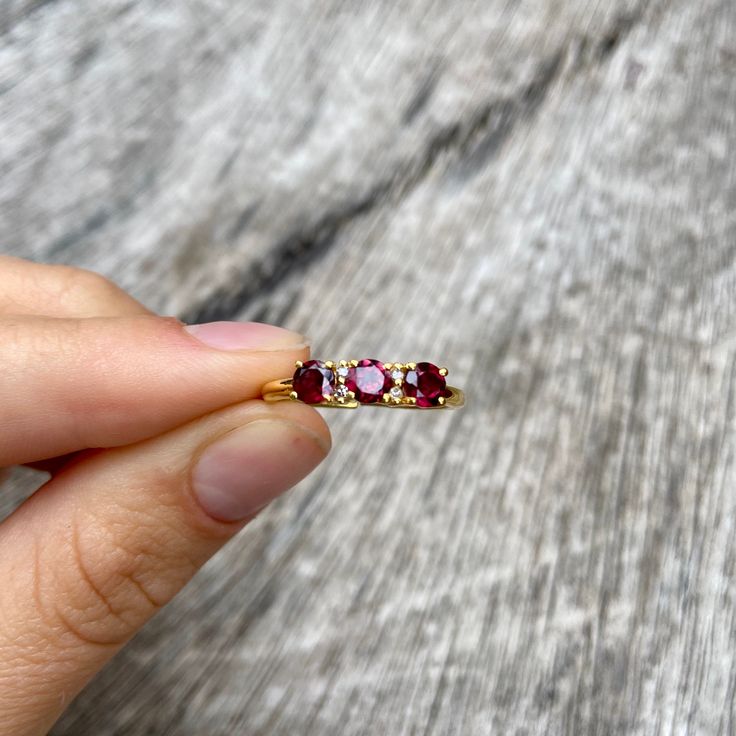 Three gorgeous little faceted garnet gemstones flanked with two tiny diamonds besides the middle one and set in gold vermeil. The open band is adjustable allowing it to be sized up a size. Gold Rings With Rose Cut Diamonds And Garnet, Gold Garnet Ring With Rose Cut Diamonds, Ruby Ring With Rose Cut Diamonds Gift, Garnet Promise Ring With Rose Cut Diamonds, Garnet Rings With Rose Cut Diamonds For Promise, Ruby Ring With Rose Cut Diamonds, Dainty Ruby Birthstone Ring, Burgundy Ruby Rings With Gemstone, Burgundy Ruby Ring With Gemstone