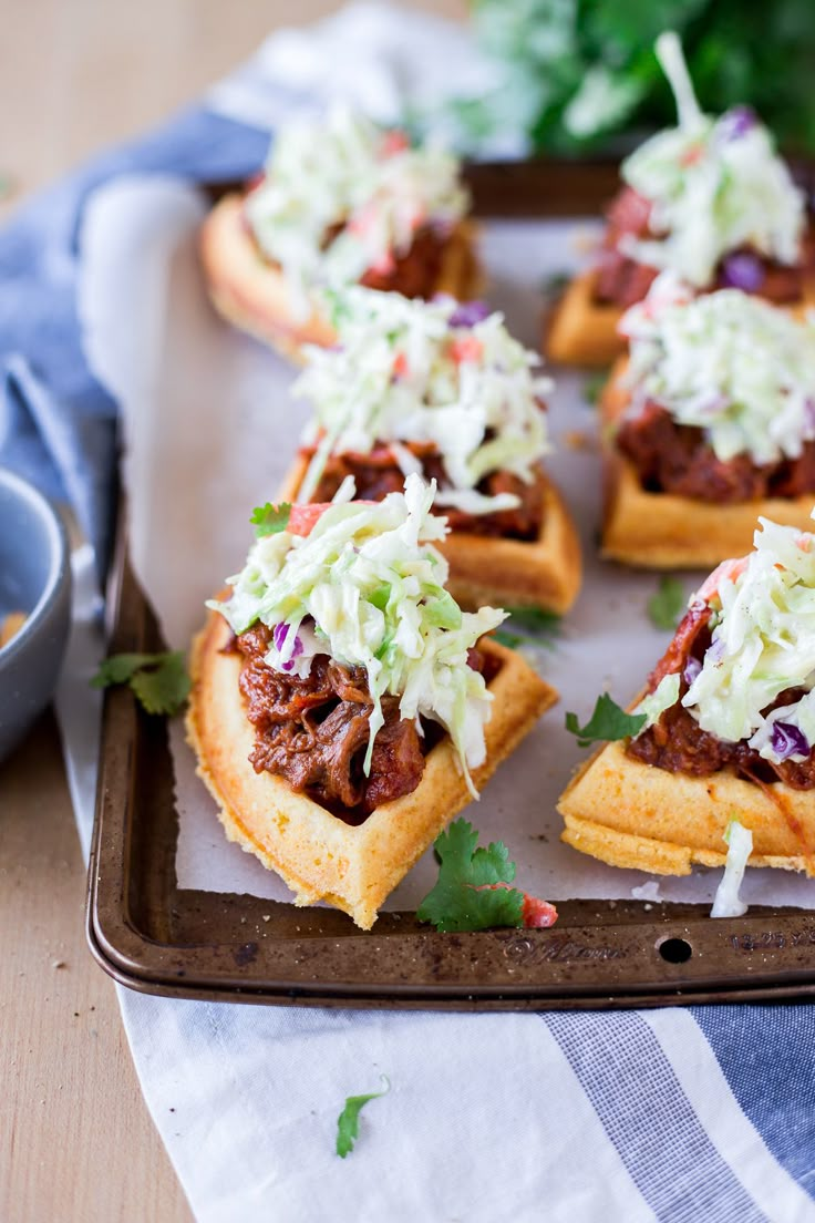 small waffles with meat and coleslaw on them sitting on a tray