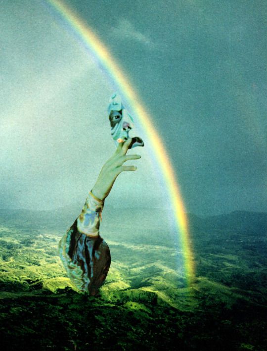 a person reaching up into the sky with a rainbow in the background