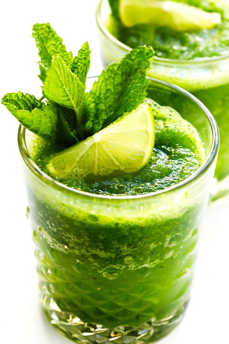 two glasses filled with green smoothie and lime