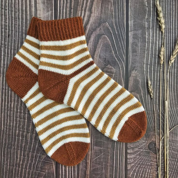 two brown and white socks sitting on top of a wooden floor next to a plant