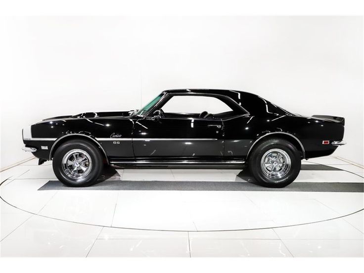 a black muscle car parked in a white room