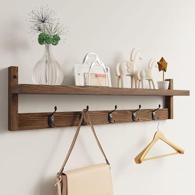 a wooden shelf with hooks and purses on it next to a wall mounted coat rack