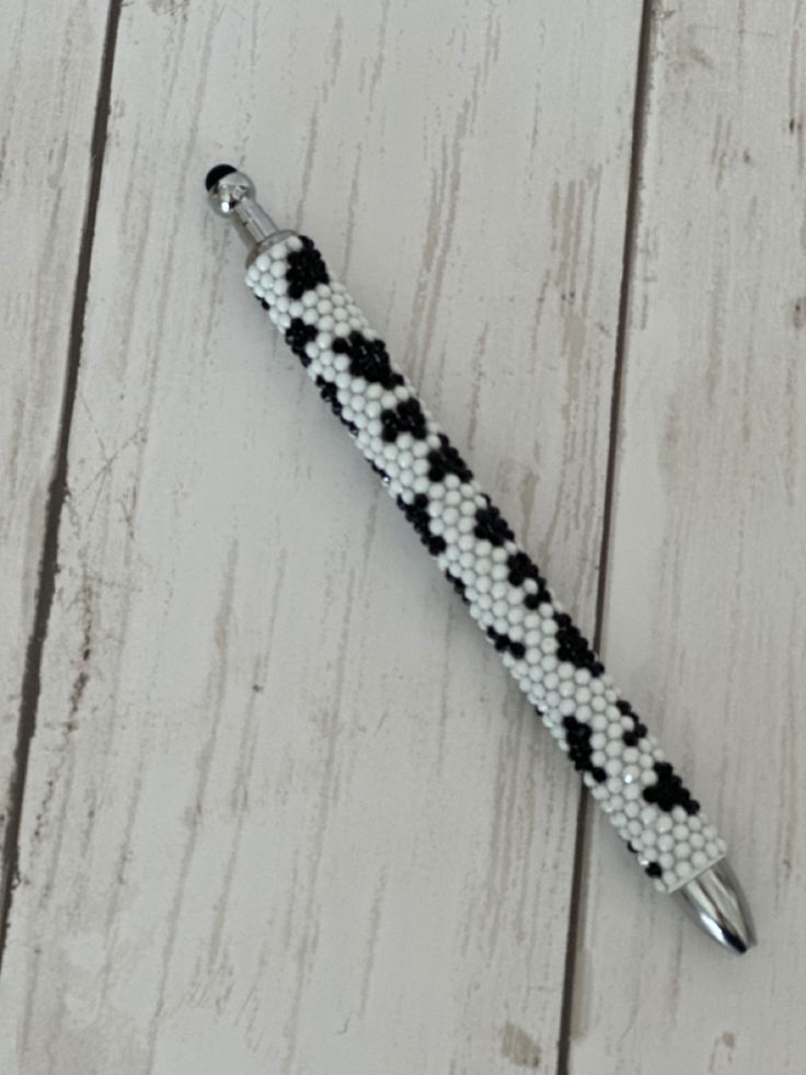 a black and white beaded pen sitting on top of a wooden table