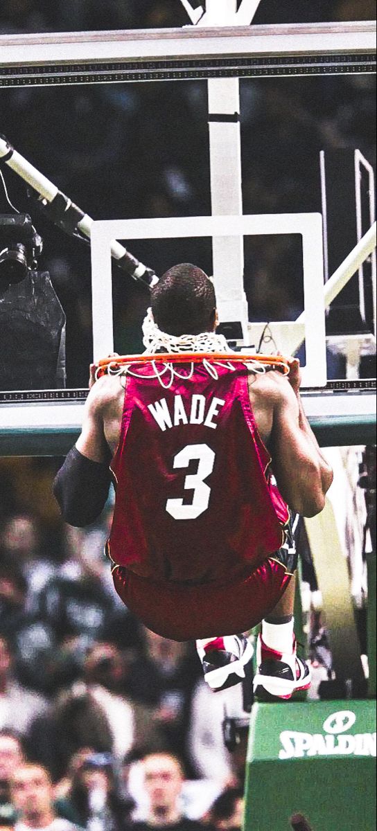 a basketball player dunking the ball in front of an audience at a sporting event