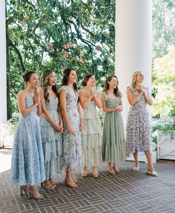 a group of women standing next to each other on top of a brick floor covered porch