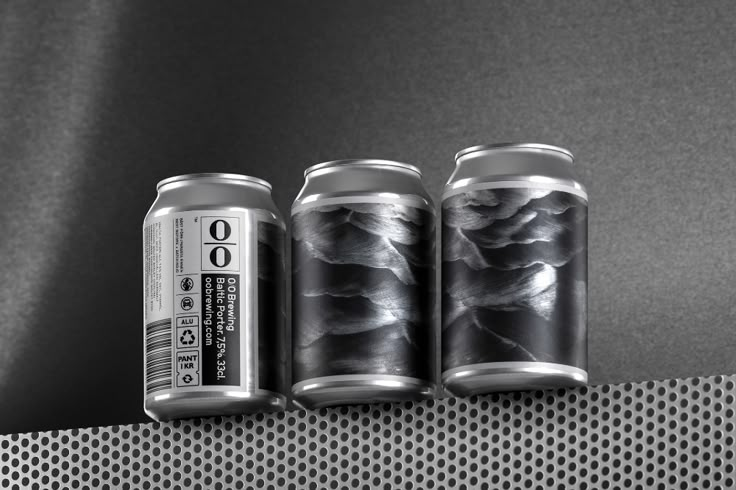 three cans of soda sitting next to each other on a metal shelf in front of a black and white background