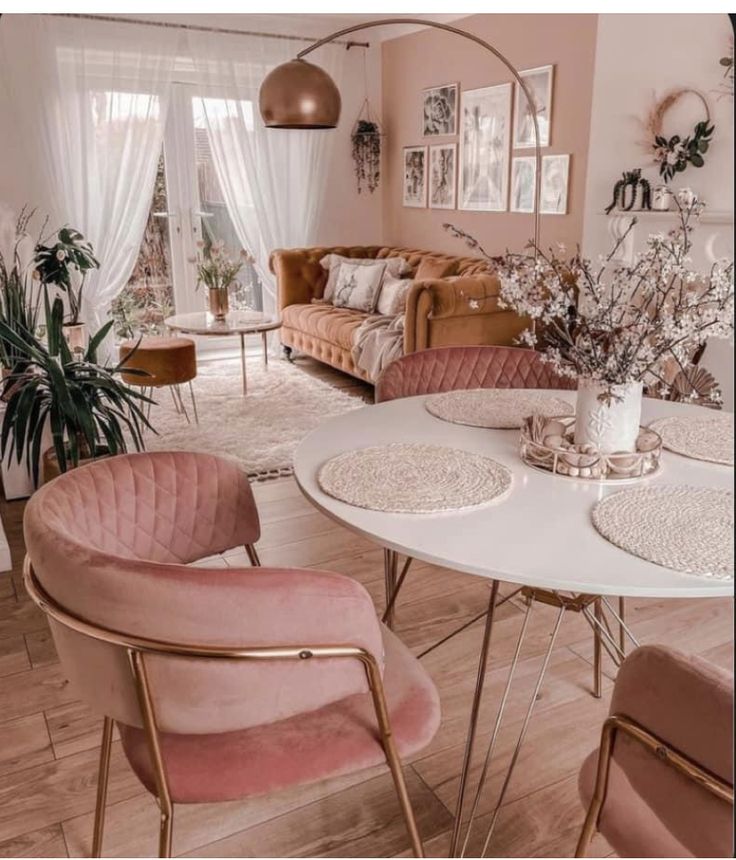 a living room filled with furniture and a white table surrounded by pink chairs, rugs and potted plants