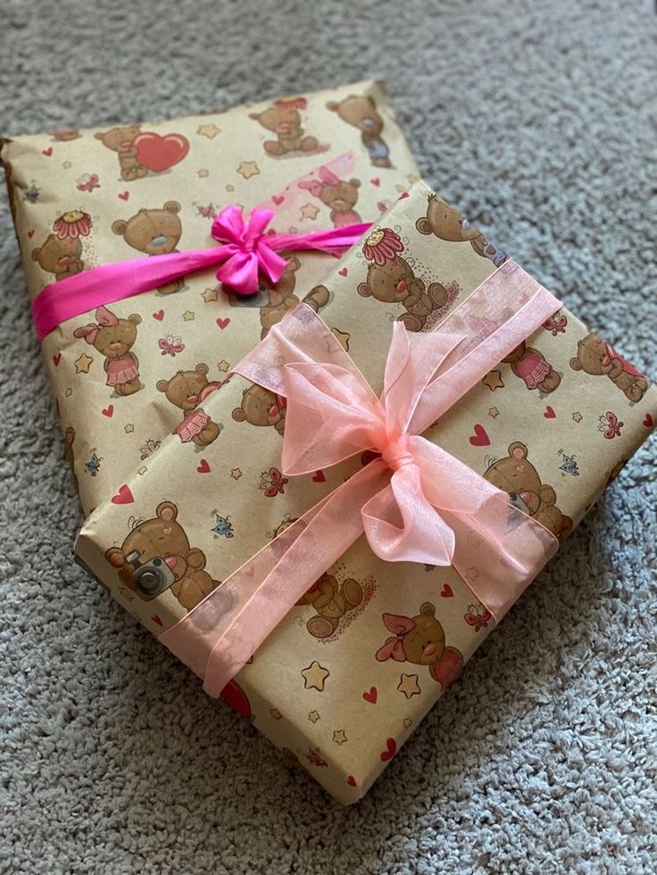 a wrapped gift box on the floor with pink ribbon