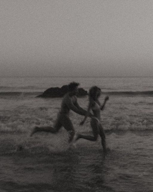 two people running in the water at the beach