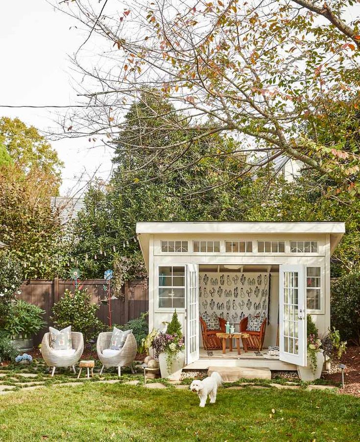 a small white shed sitting on top of a lush green field