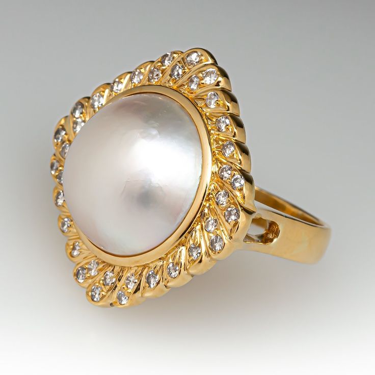 This fabulous vintage cocktail ring is centered with one (1), bezel set, round maybe' pearl and is bordered with thirty-six (36), bead set, round brilliant cut diamond. The ring measures 24.9mm at the top, rises 11.0mm above the finger, tapering to 3.4mm wide and 1.1mm thick at the base of the shank. The ring is currently size 6.5. Formal Jewelry With Fluted Bezel, Elegant Diamond Ring With Fluted Bezel For Anniversary, Elegant Wedding Watch With Fluted Bezel, Elegant Cabochon Rings For Anniversary, Elegant Wedding Jewelry With Fluted Bezel, Anniversary Yellow Gold Pearl Ring With Cabochon, Classic Cabochon Pearl Ring For Formal Occasions, Luxury Pearl Cabochon Ring For Formal Occasions, Luxury Cabochon Pearl Ring For Wedding