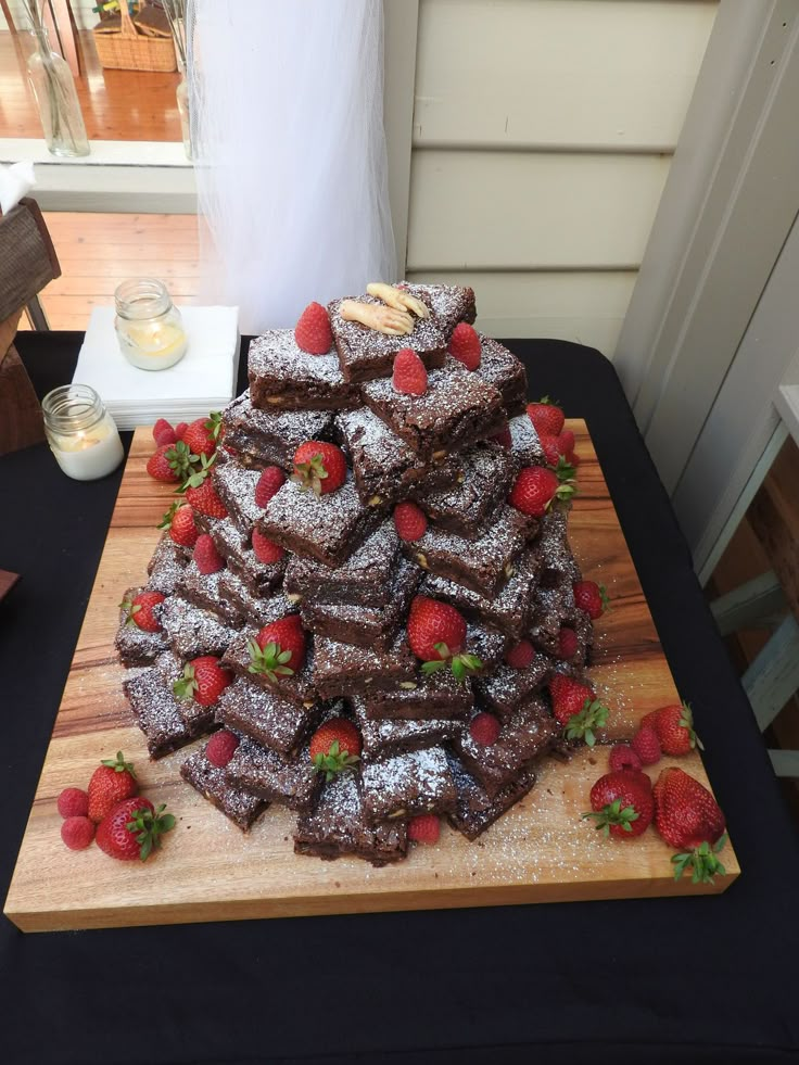 a wooden cutting board topped with brownies and strawberries