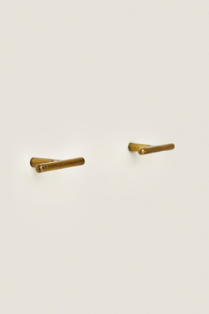 two gold ear pins sitting on top of a white surface with no one in it