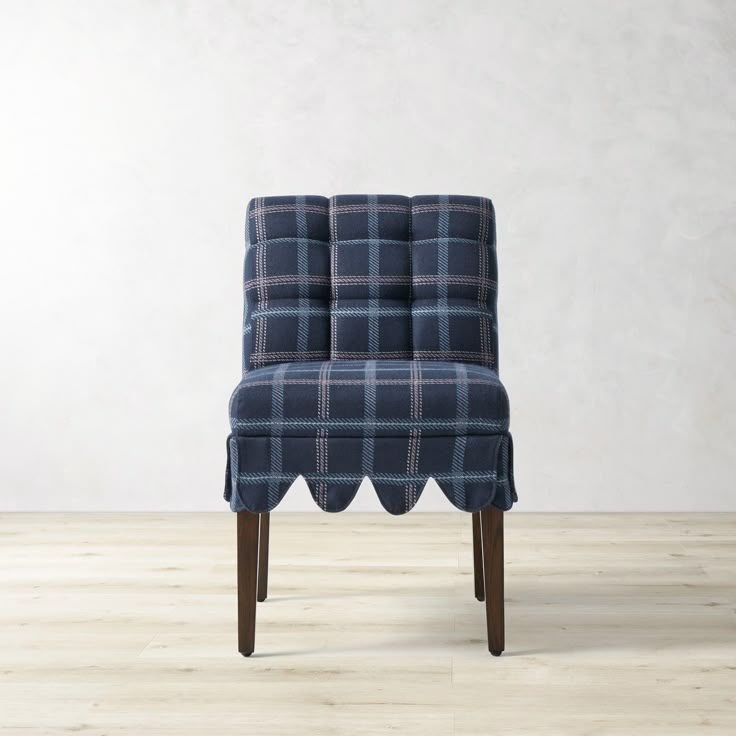 an upholstered chair with scalloped legs and a blue checkered seat cover