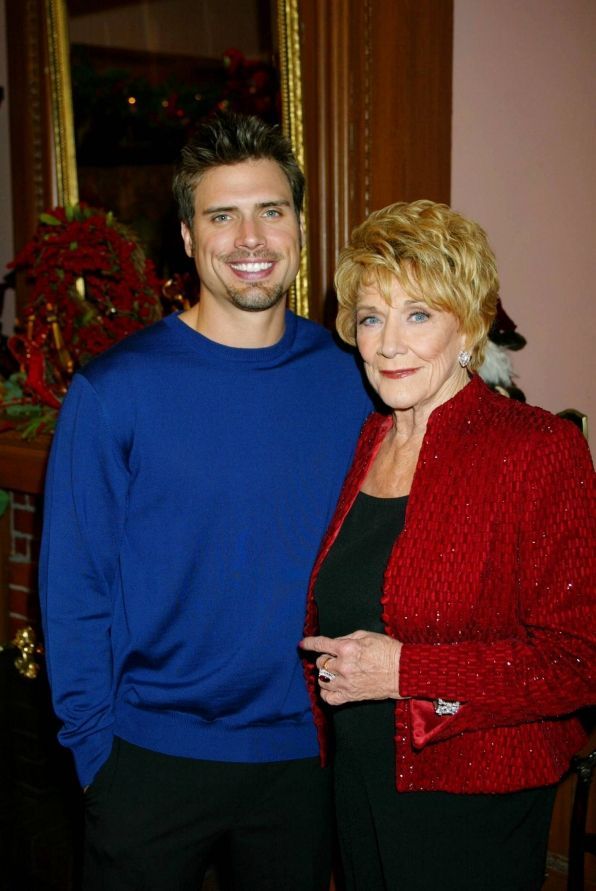 a man and woman standing next to each other in front of a christmas tree with decorations