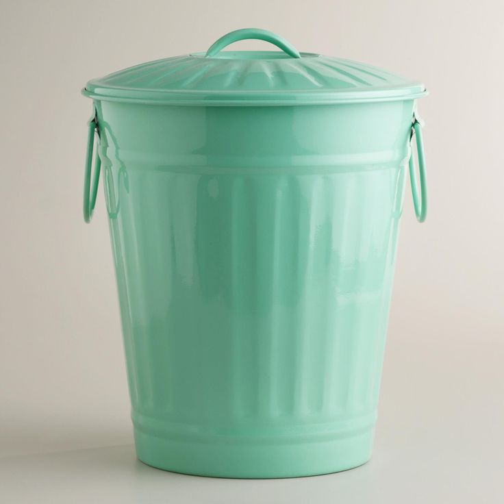 a large green trash can sitting on top of a white floor next to a wall