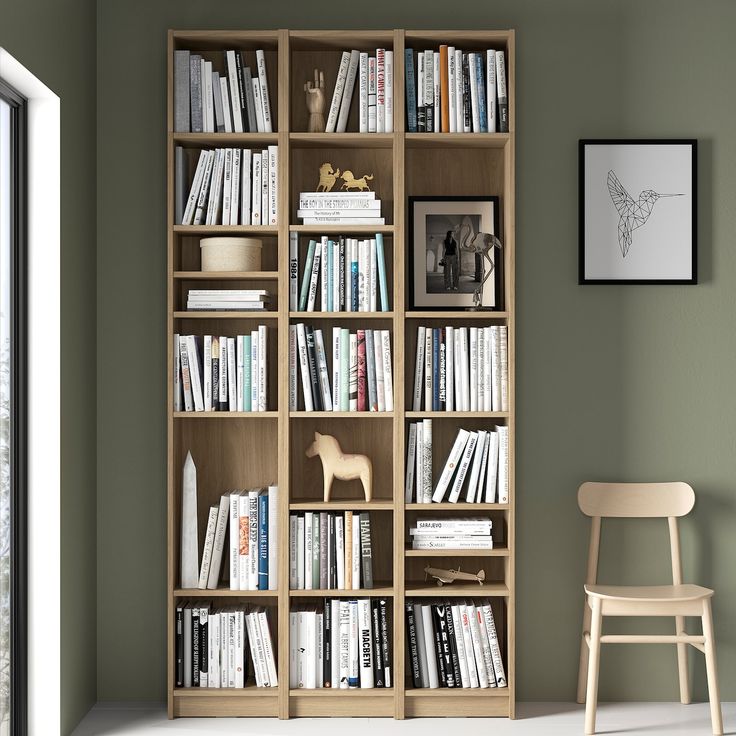 a book shelf filled with lots of books next to a white chair and framed photograph