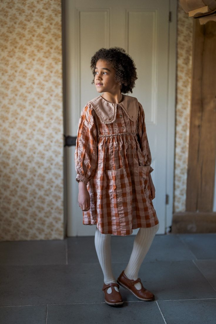 Our Lottie dress is made in our organic seersucker gingham fabric. It has full sleeves which extend from the bodice giving a floaty, voluminous feel, the fit is easy and therefore very comfortable. The contrasting cotton collar has a gathered fabric edge and embroidery stitch detail. Made from 100% Organic Cotton Garment Care: Wash at 30 degrees with like colours, wash inside out, iron on reverse. Sizing Size 2-3 years - Dress length: 54cm, chest: 74cm Size 3-4 years - Dress length: 57cm, chest: Lottie Dress, Gathered Fabric, Embroidery Stitch, Cotton Clothes, Striped Pyjamas, Gingham Fabric, Organic Cotton Clothing, Folk Fashion, Special Dresses