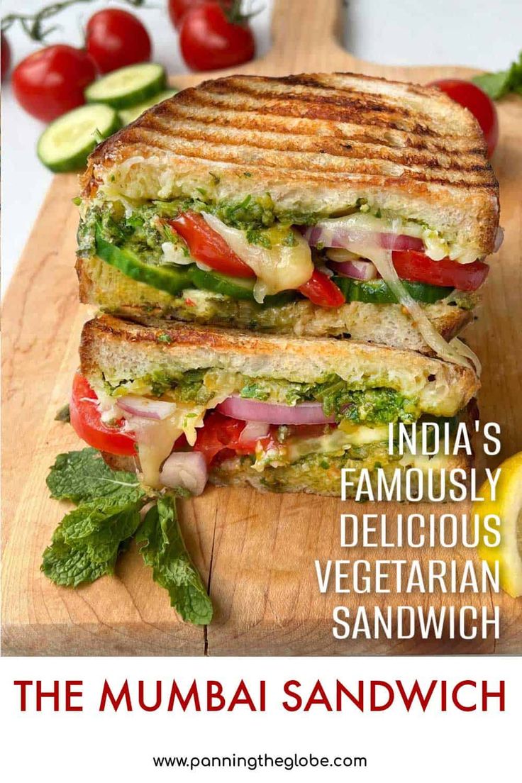 the mumbai sandwich is cut in half on a cutting board with tomatoes and cucumber