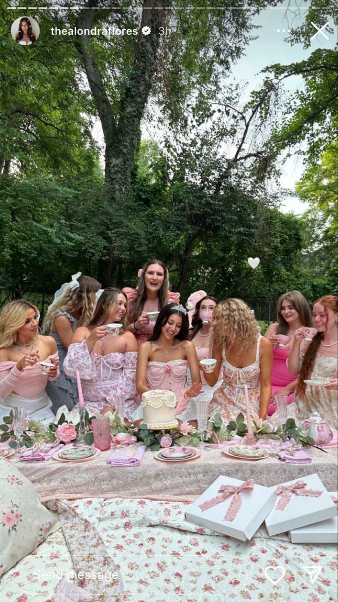 a group of women in pink dresses standing around a table with cake and flowers on it