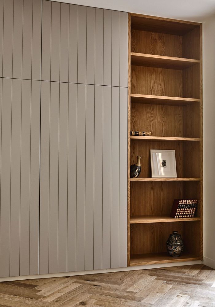 an open bookcase in the corner of a room next to a wall with wooden paneling