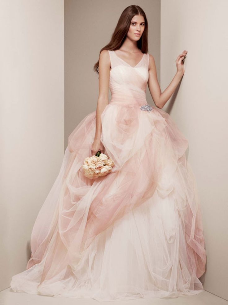 a woman in a pink wedding dress holding a white bouquet and posing for the camera