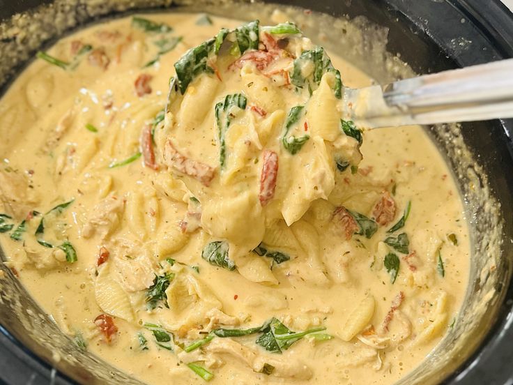 a bowl filled with pasta and spinach on top of a stove