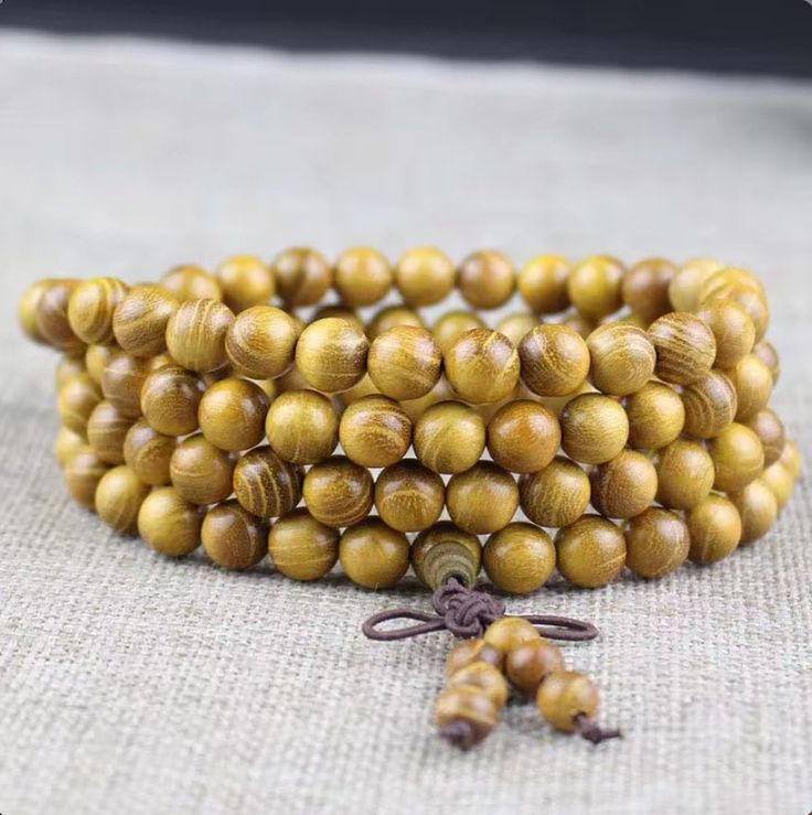 Ditch the basic, embrace the cosmic glow-up with this 8mm golden wood mala. Hand-knotted by mountaintop monks in a secret Thai monastery, these beads drip with golden light - the kind that attracts prosperity and good vibes like nobody's business. Each bead whispers of the monastery's tranquility, amplifying your every mantra. This ain't your average wrist candy; it's a portal to cultivating inner wealth, laser-sharp focus, and a meditation experience that's pure luxury. Level up your practice, radiate good karma, and support the monastery's mission - all with this one golden ticket to zen. Golden Ticket, Wrist Candy, Glow Up?, Charms, Meditation, Pure Products, Beads, Wood