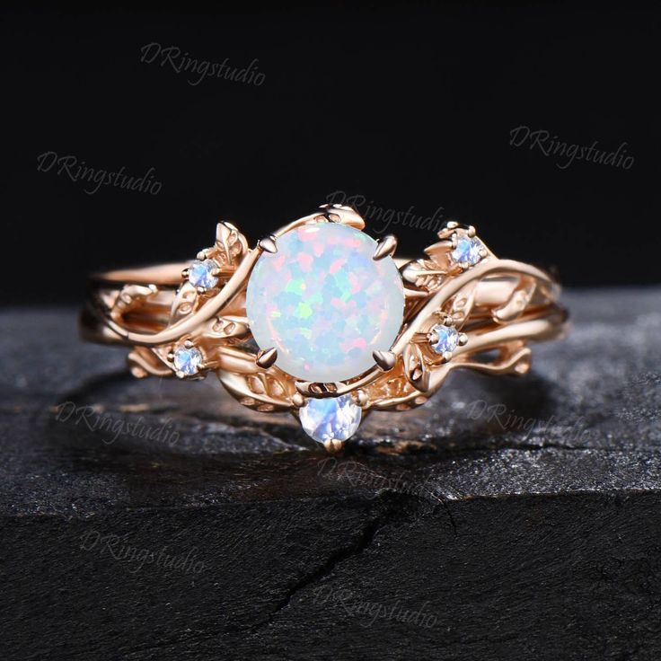 an opal and diamond ring set on top of a stone slab with black background