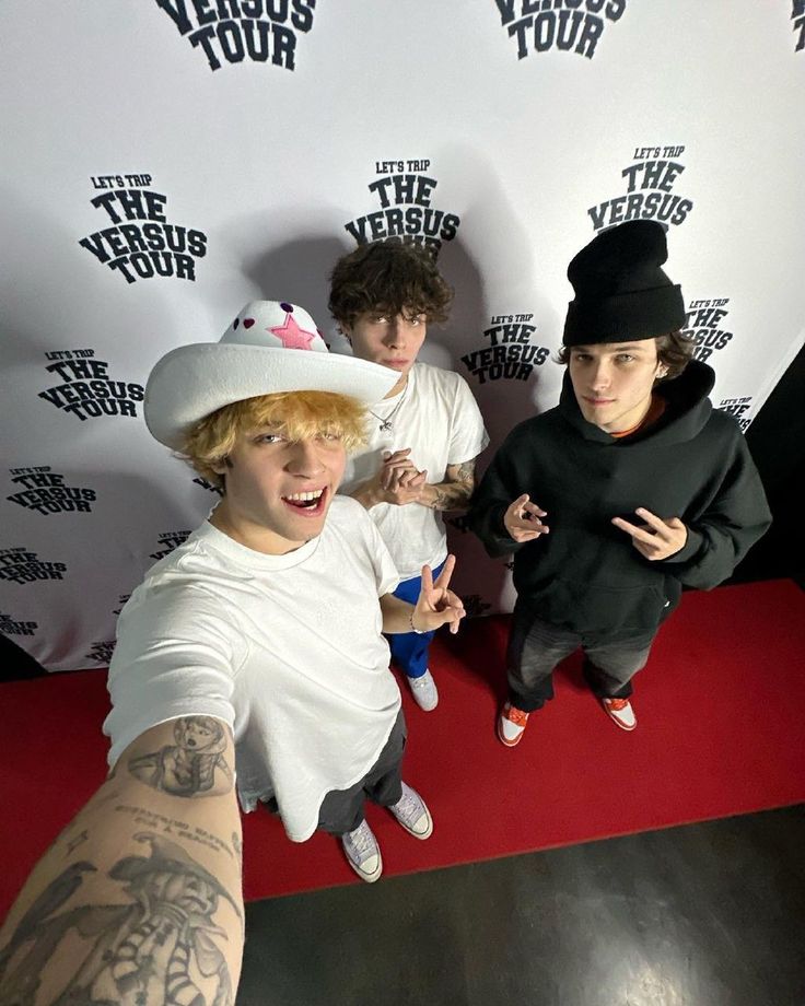 three young men standing in front of a red carpet