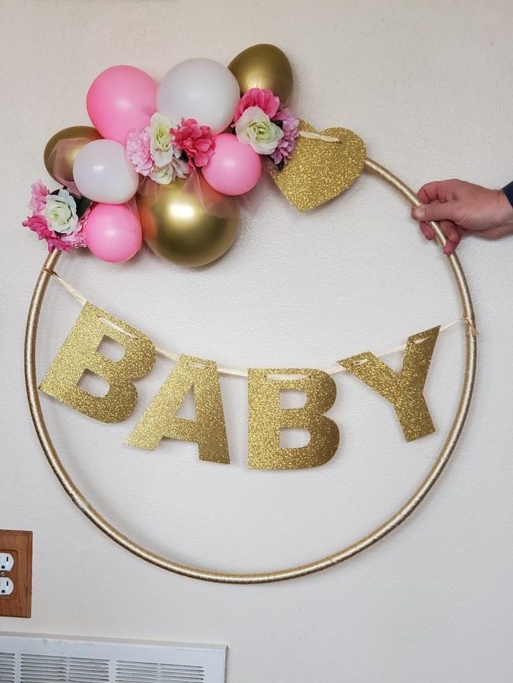 a baby shower decoration with balloons and flowers on the wall next to an air conditioner