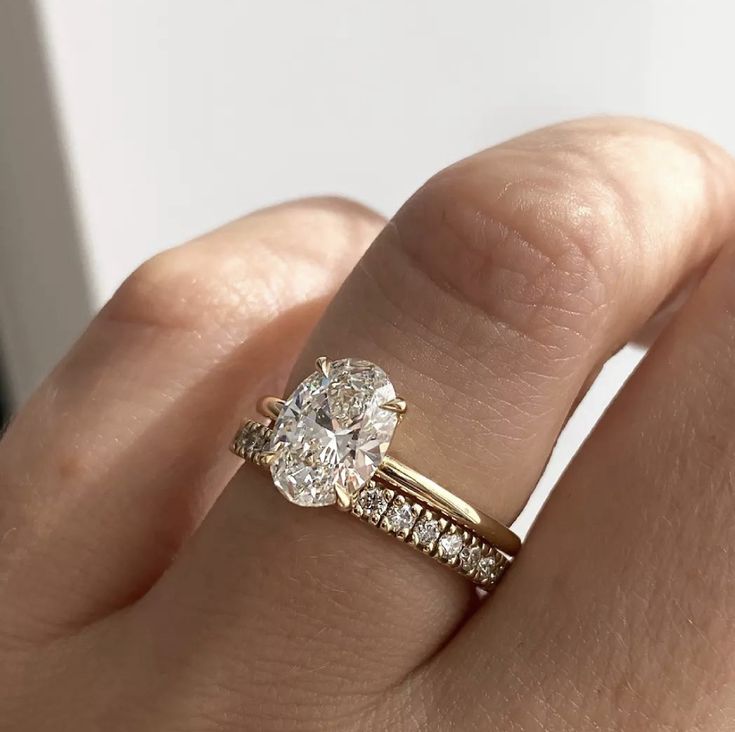 a woman's hand with a diamond ring on top of her finger and the engagement band