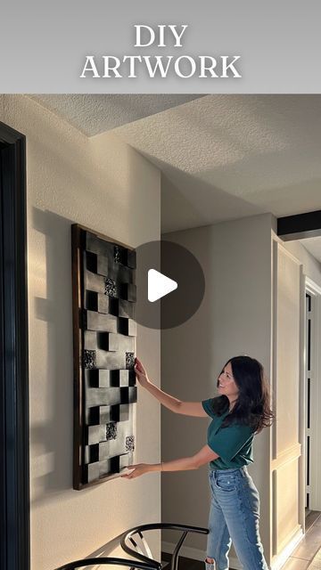 a woman standing in front of a black and white checkered wall hanging on the wall