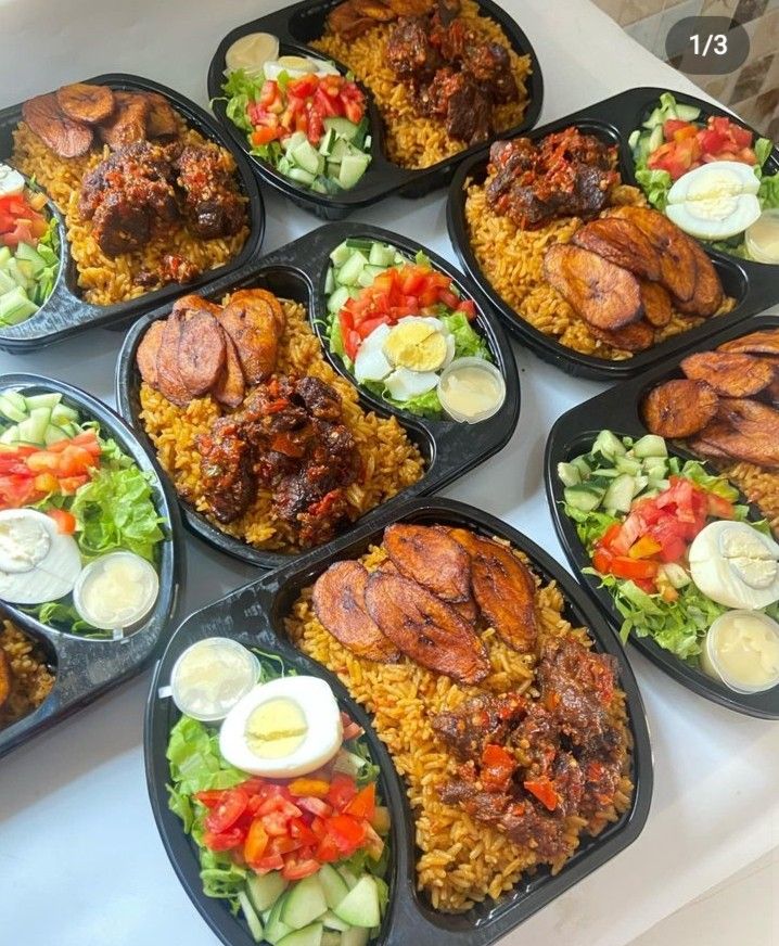 a table topped with black trays filled with different types of food covered in plastic containers